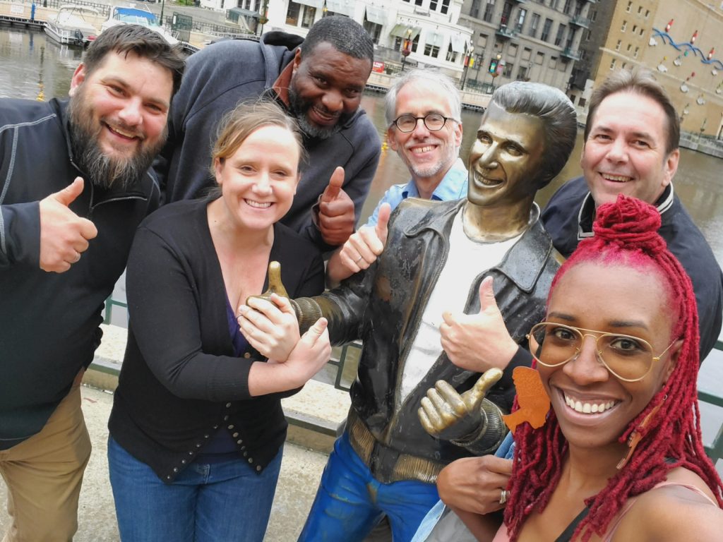 Adults posed with statue on a pier.